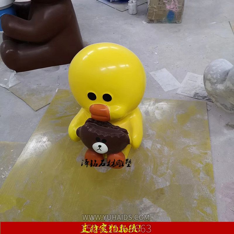 公園里一只抱著(zhù)熊頭的玻璃鋼卡通鴨子雕塑