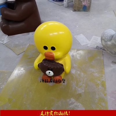 公園里一只抱著(zhù)熊頭的玻璃鋼卡通鴨子雕塑